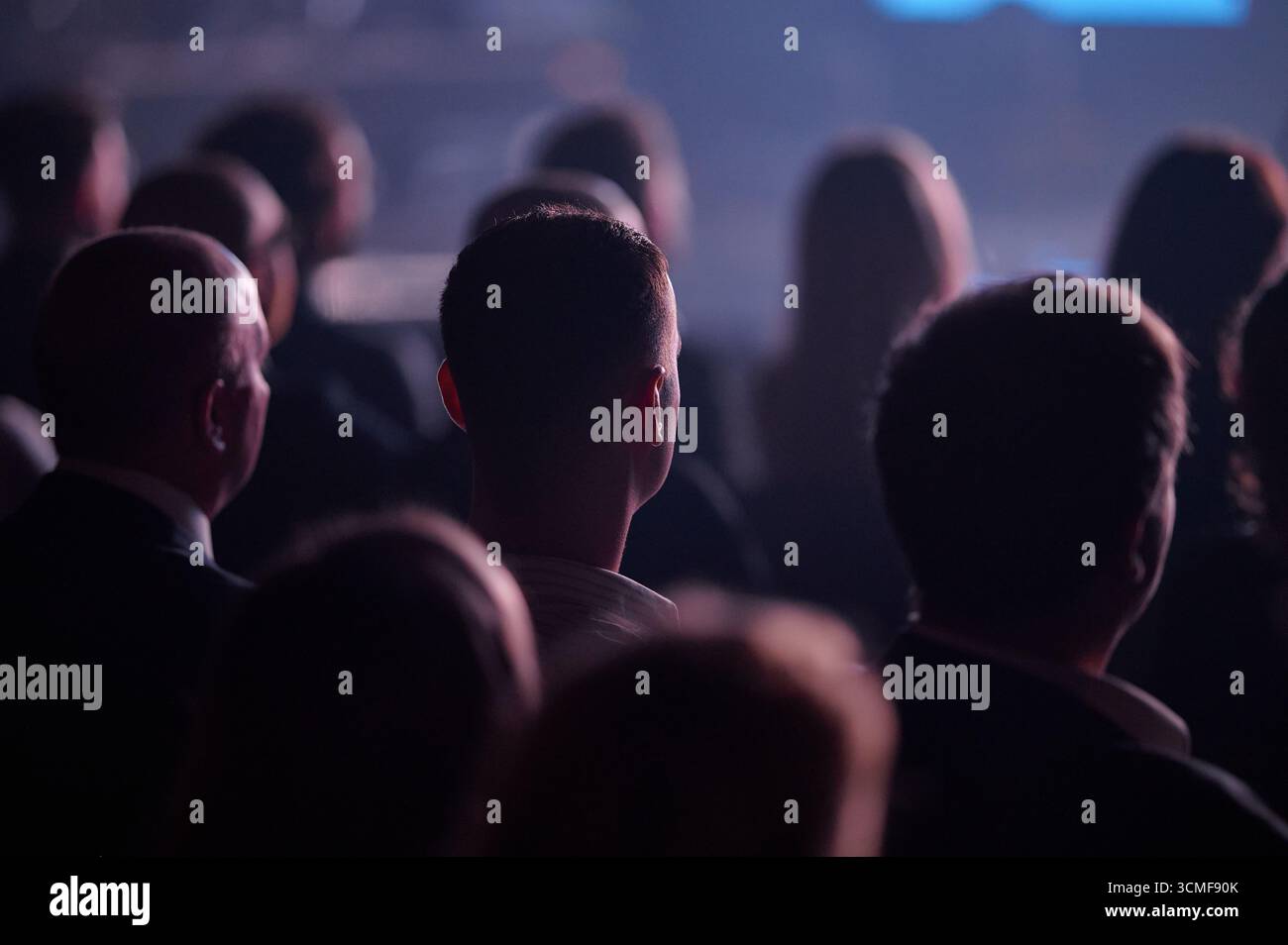 Vista posteriore del pubblico durante la conferenza di Gdynia, riflettori sull'illuminazione del bordo della testa, teleobiettivo paesaggistico bokeh, atmosfera coinvolgente, utile per il keynote aziendale brochu Foto Stock