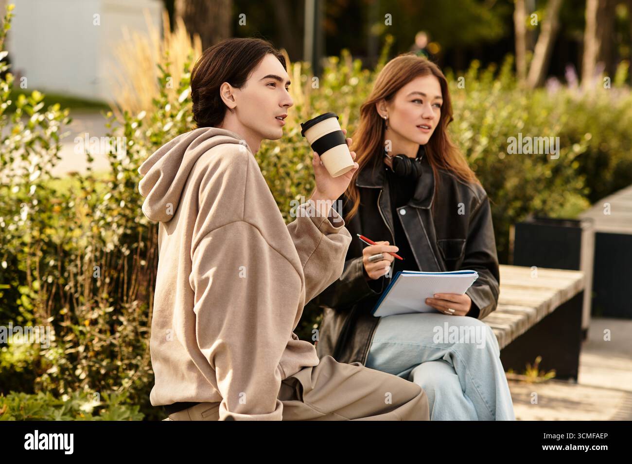 Una coppia si siede insieme in un bellissimo ambiente all'aperto, condividendo pensieri e risate. Foto Stock