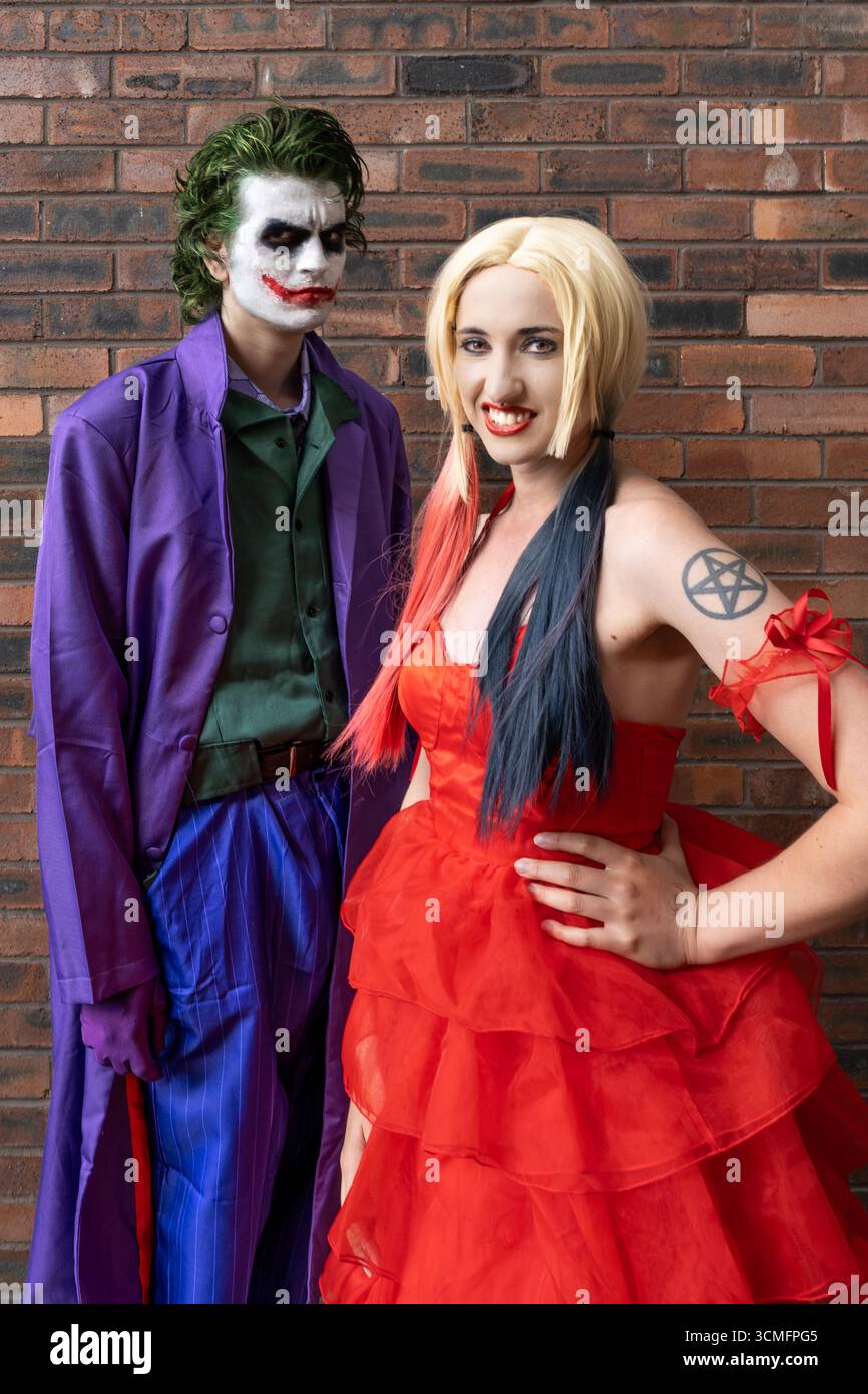 Una bella ragazza e un bel cosplayer maschio che si diverte e ride mentre si vestono da Joker e Harley Quinn con spazio per copiare sopra Foto Stock