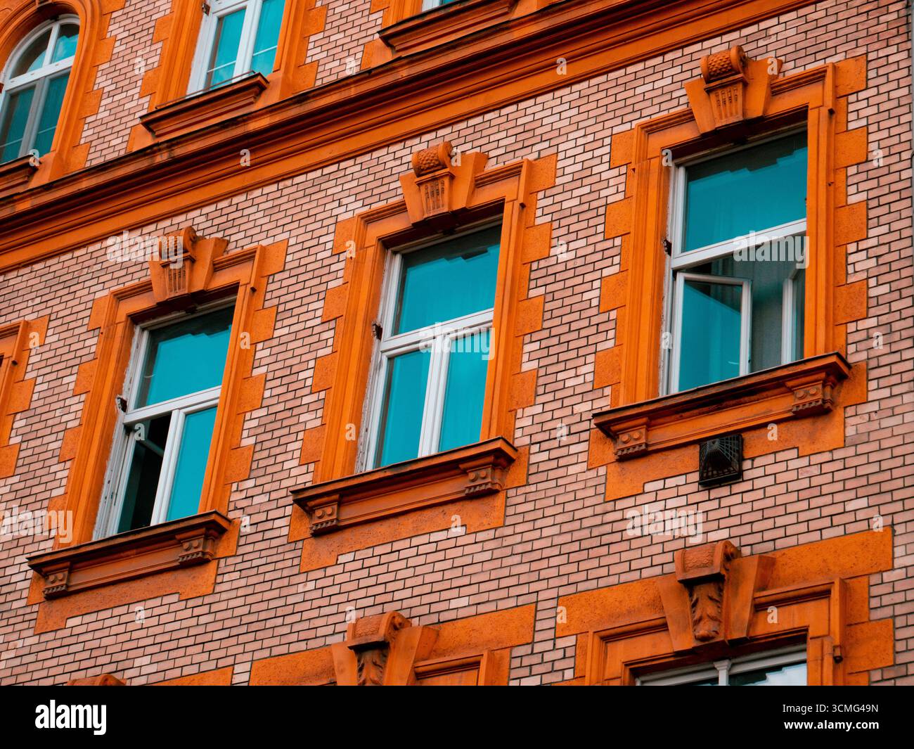 Facciata in mattoni con dettagli arancioni e riflessi finestra blu Foto Stock