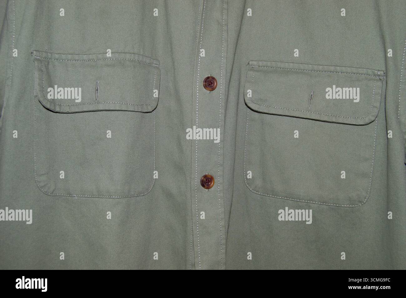 Dettaglio ravvicinato di una camicia verde stile militare da uomo che mostra due tasche con pattina sul petto e bottoni. Vista frontale del tessuto di camicia casual in cotone verde oliva tex Foto Stock