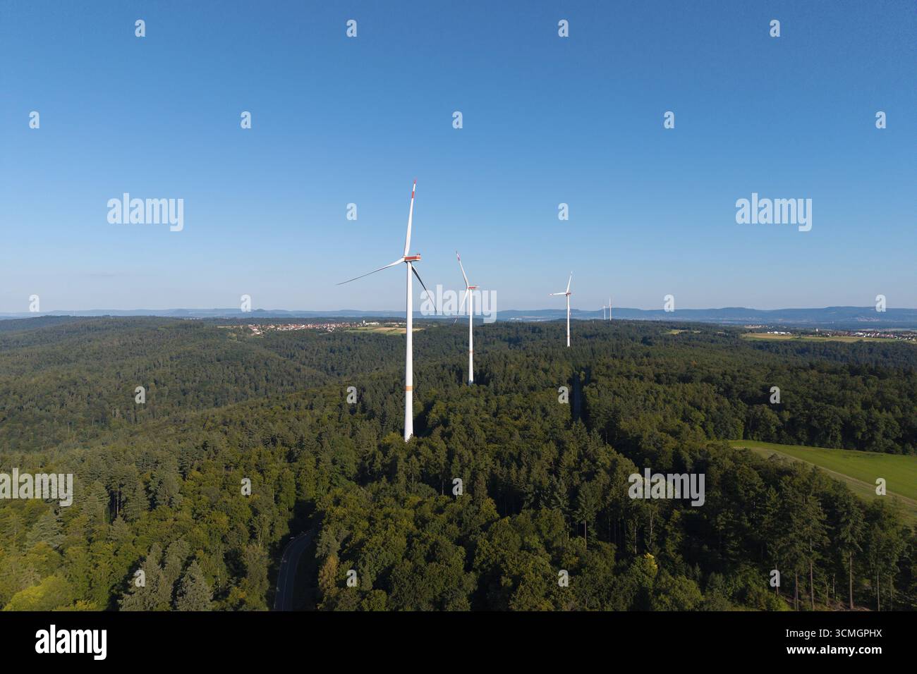 Turbine eoliche sopra foreste verdi sotto un cielo blu, simbolo dell'energia pulita, vicino a Schorndorf a Remstal, Baden-Wuerttemberg, Germania Foto Stock