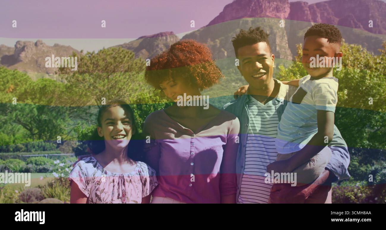 Famiglia di quattro persone con abiti primaverili in un giardino paesaggistico, con arbusti fioriti e montagne Foto Stock