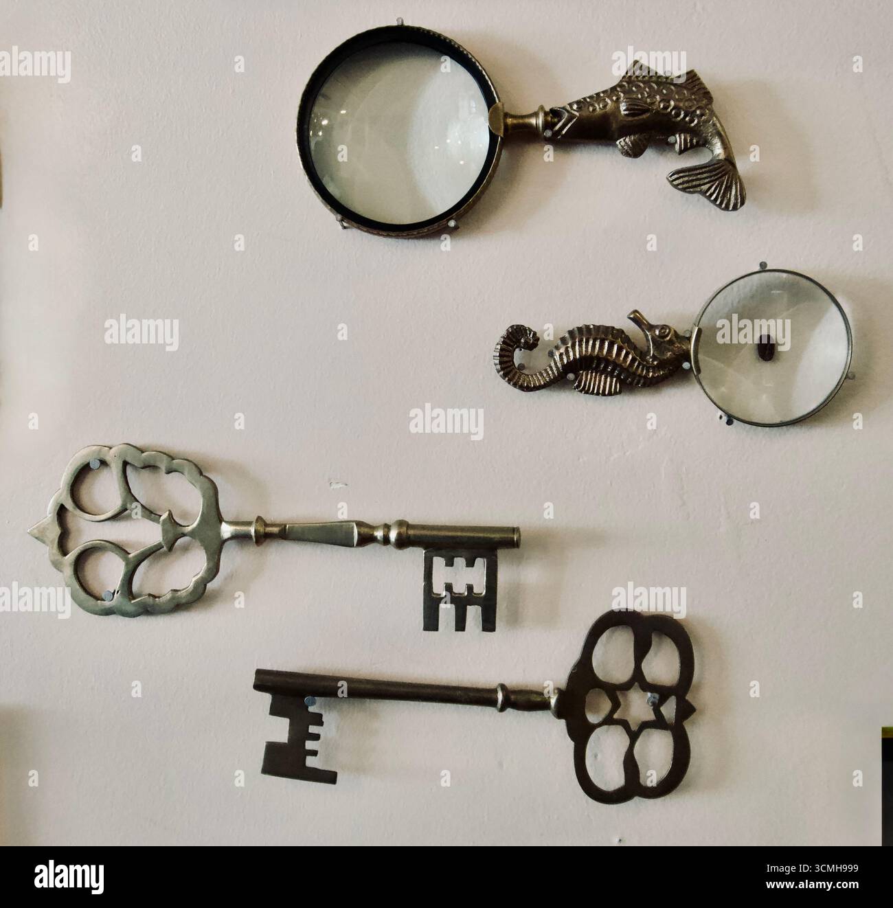 Lenti d'ingrandimento vintage e decorazioni a parete con chiavi antiche Foto Stock