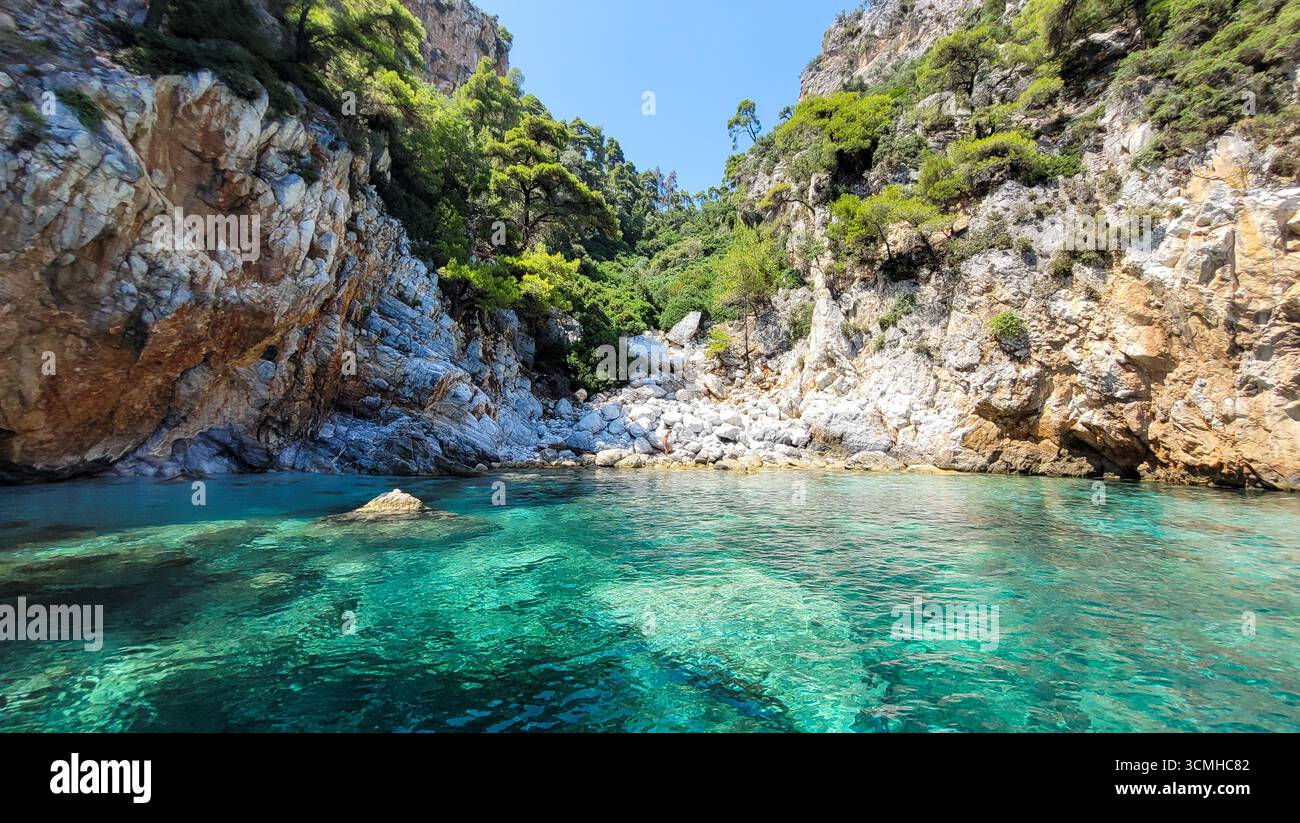 Un'insenatura isolata con acque turchesi incontaminate e una spiaggia di ciottoli nascosta vicino ad Amarandos, all'isola di Skopelos, in Grecia Foto Stock
