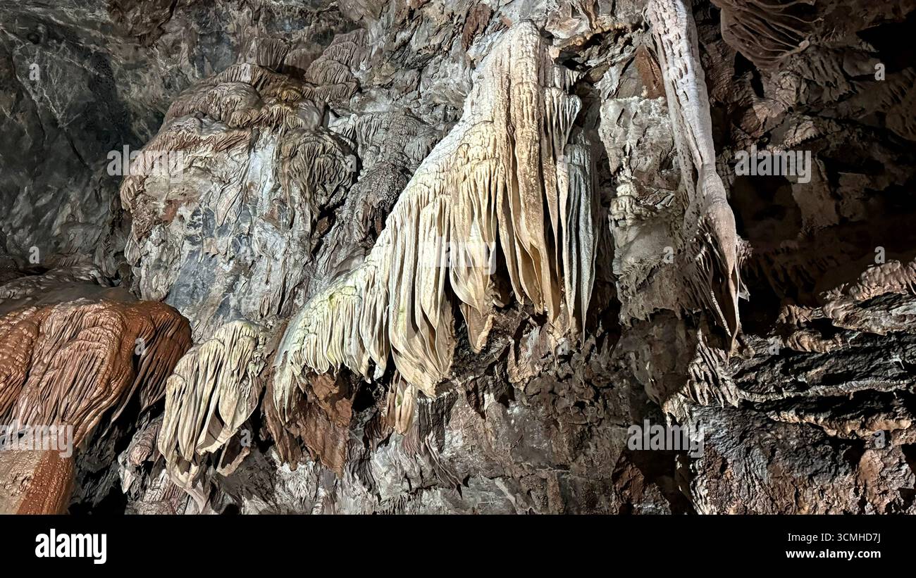 Tendaggi di Flowstone simili a tende in una grotta di pietra calcarea Foto Stock