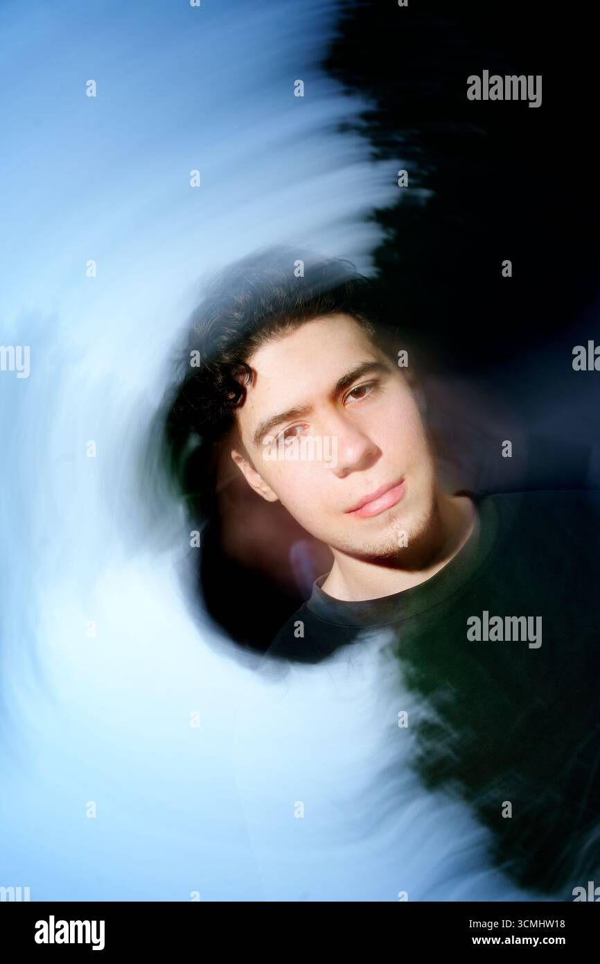 Ritratto di un giovane parzialmente oscurato da un vorticoso ed etereo effetto di luce e ombra, creando un senso di mistero e intrigo Foto Stock