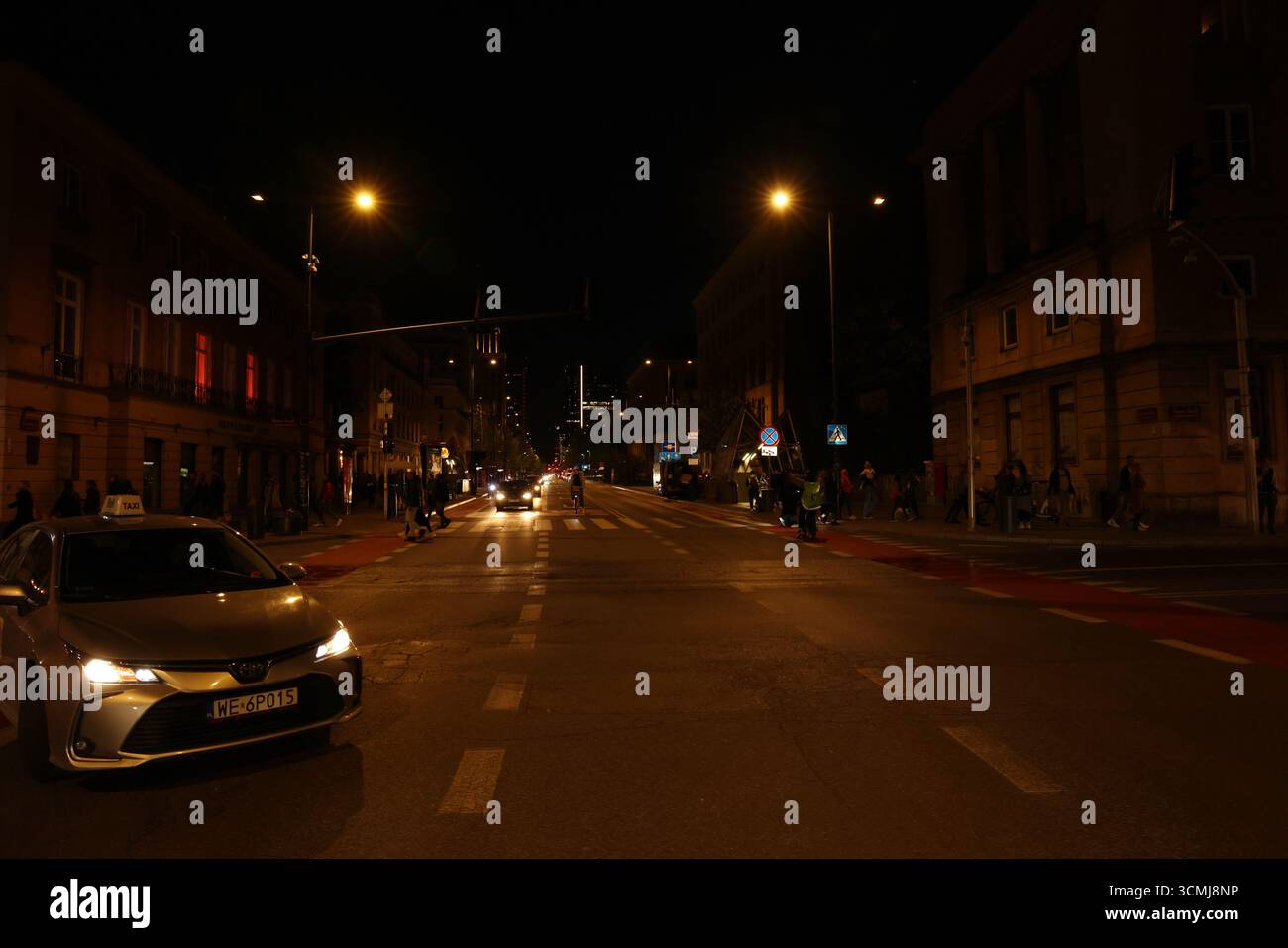 La trafficata strada notturna di Varsavia con luci accese, automobili e vivace vita notturna della città Foto Stock