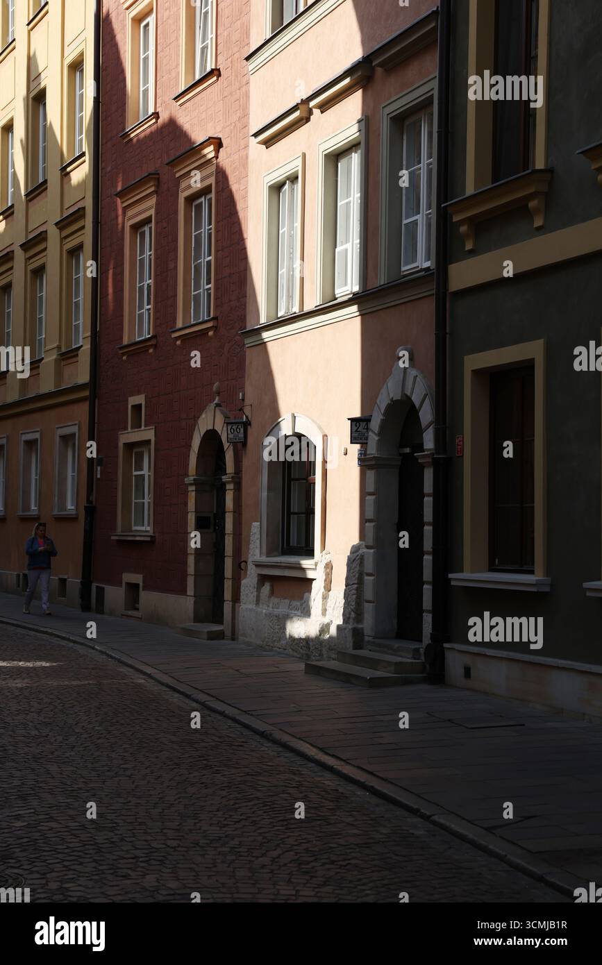 Vivace vicolo di Varsavia con ingresso storico e facciate color pastello illuminate dal sole, bellezza urbana estiva alla moda Foto Stock