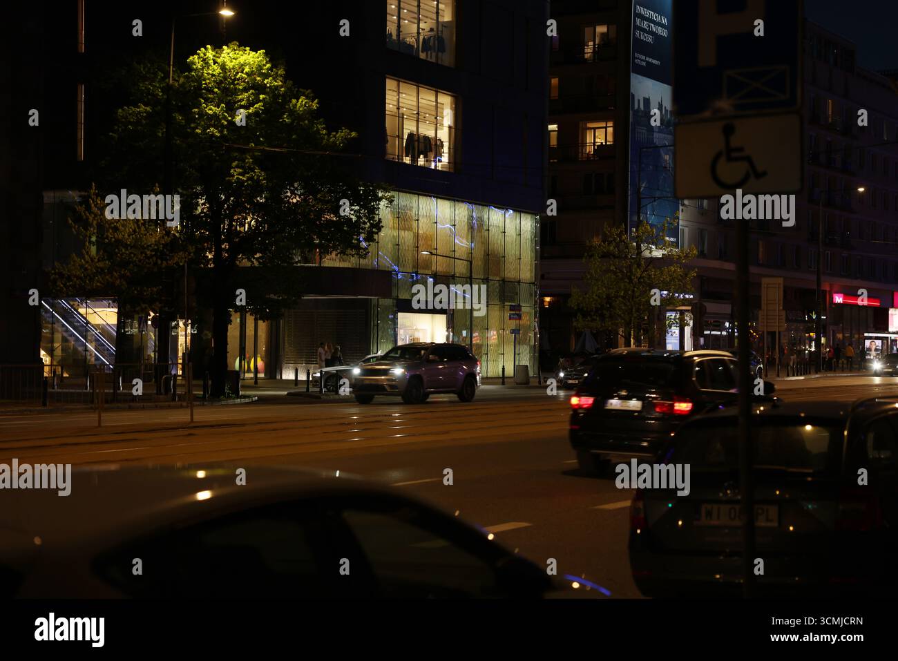 Il traffico notturno del centro di Varsavia con segnaletica illuminata al neon e sfocatura del movimento Foto Stock
