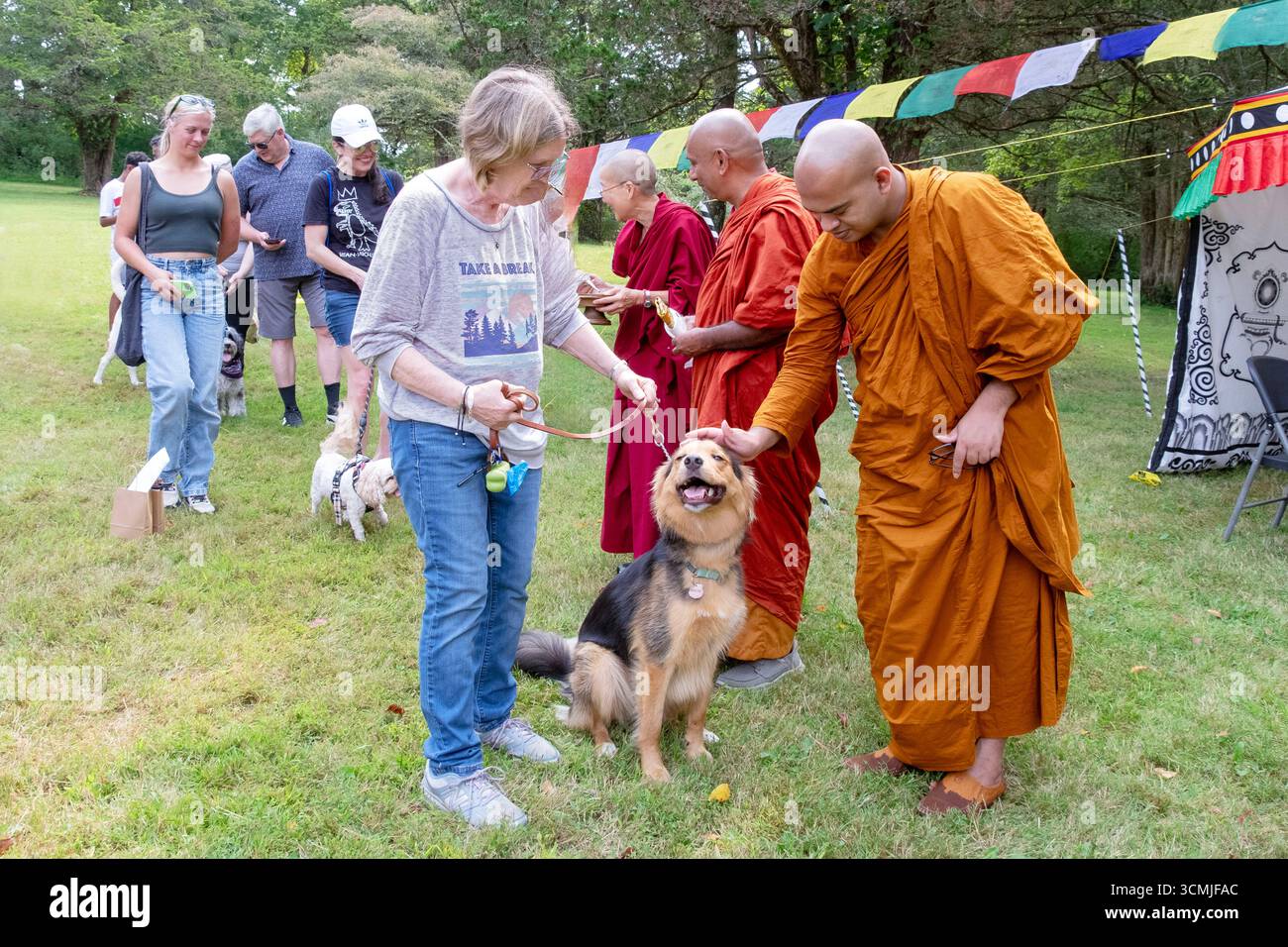 In occasione di un festival buddista tibetano di benedizione animale a Redding CT, un monaco accarezza un cane soddisfatto e felice dopo essere stato benedetto, Foto Stock