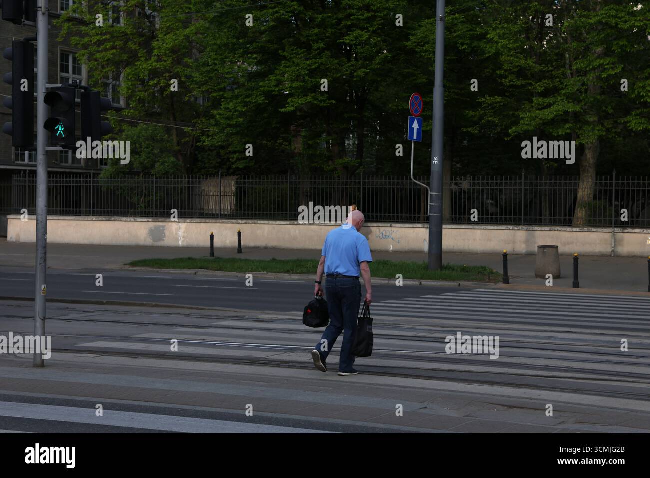 Pendolare solitario che attraversa la strada di Varsavia: Stile di vita urbano, scena cittadina minimalista Polonia Foto Stock