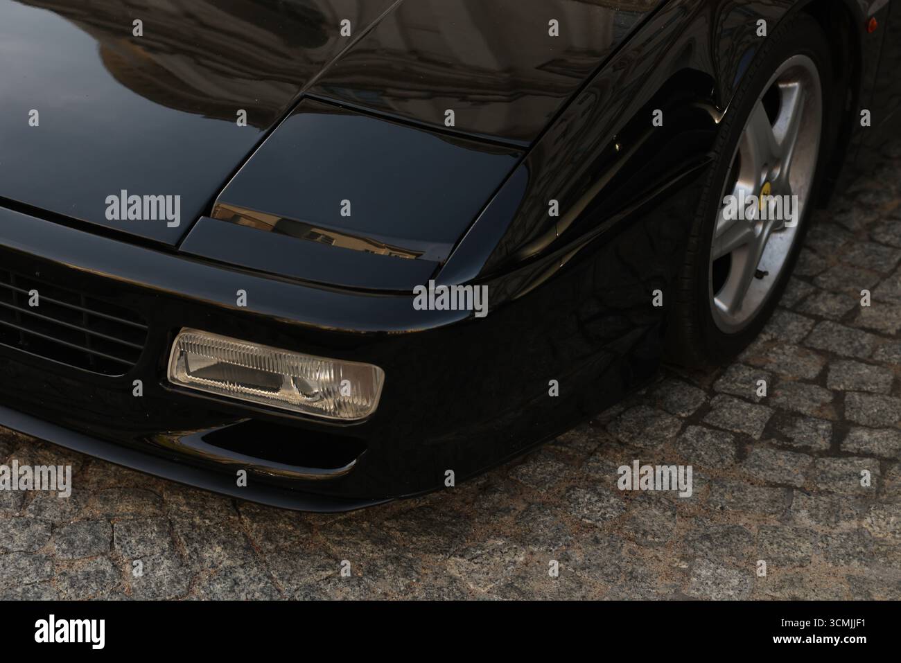 Parte anteriore della classica supercar nera su ciottoli, fari e paraurti, Varsavia Foto Stock