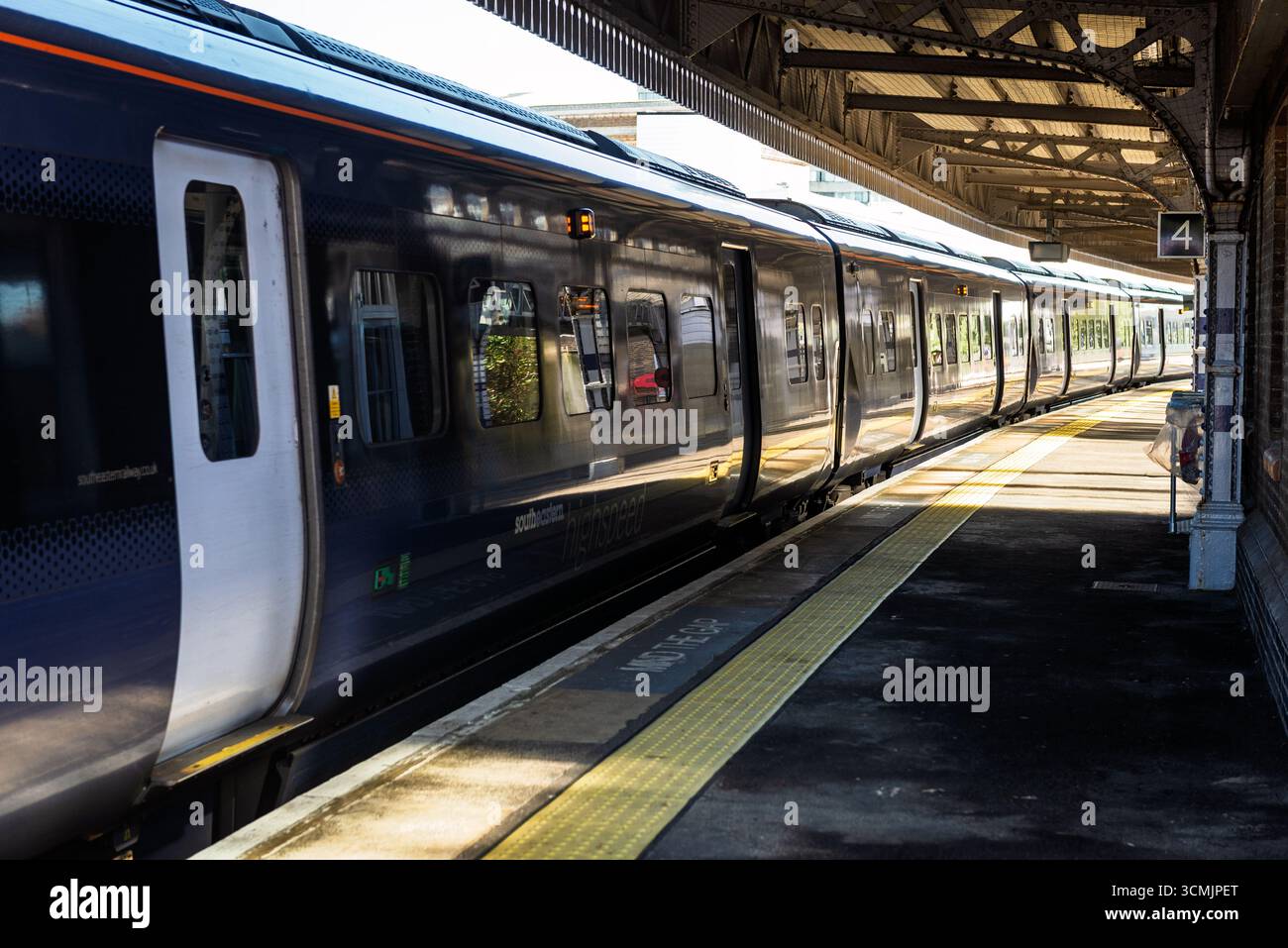 Moderno treno passeggeri con porte chiuse sulla piattaforma vuota della stazione ferroviaria Foto Stock