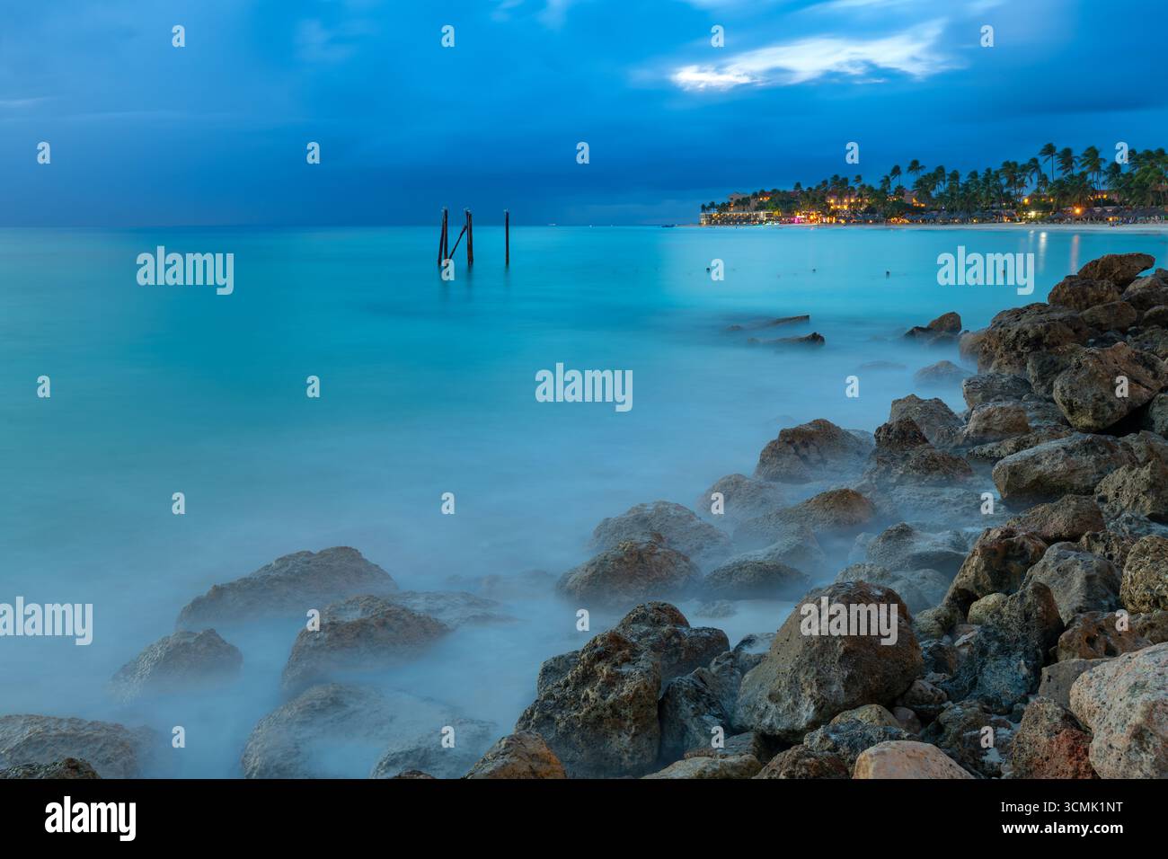 Un bellissimo tramonto a Divi Beach ad Aruba, con le dolci onde che creano una morbida nebbia intorno alle rocce costiere. Foto Stock