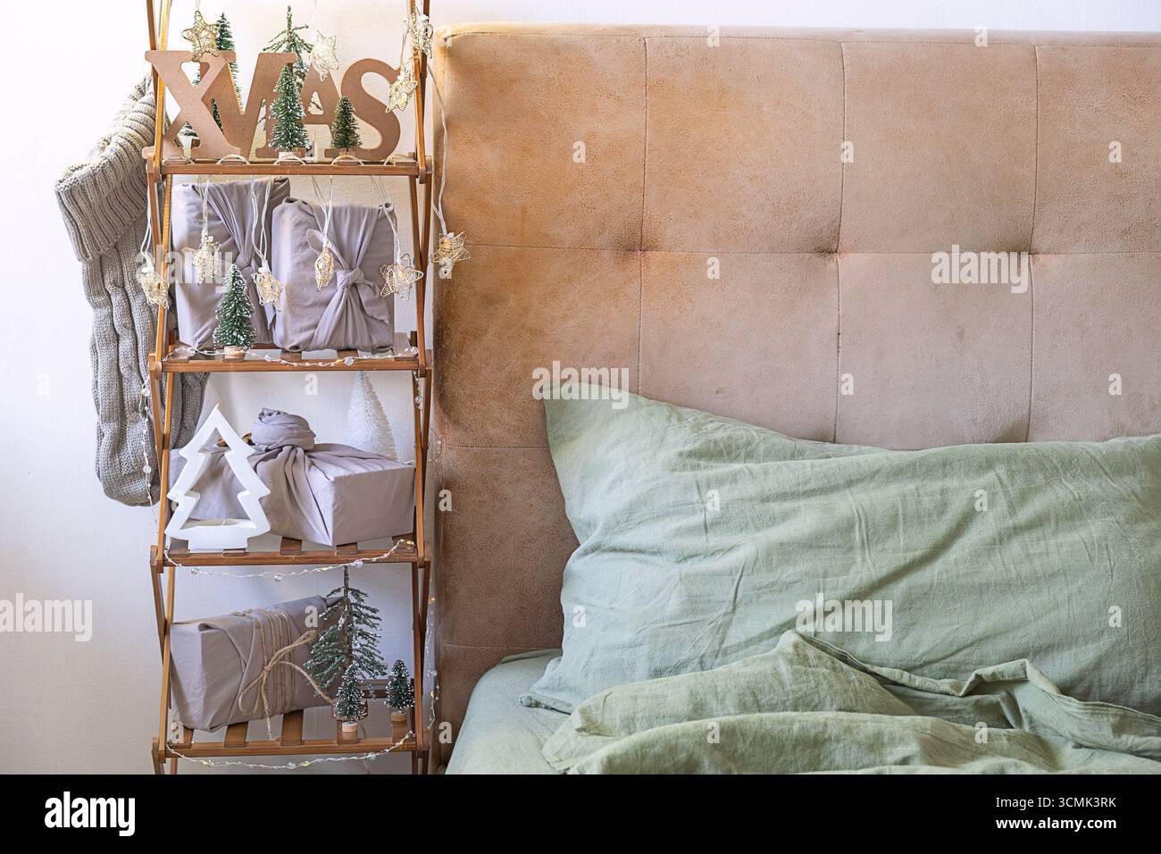 Accogliente camera da letto con decorazioni natalizie e regali. Allestimento degli interni con regali e alberi di Natale. Festività natalizie e festeggiamenti invernali. Foto Stock