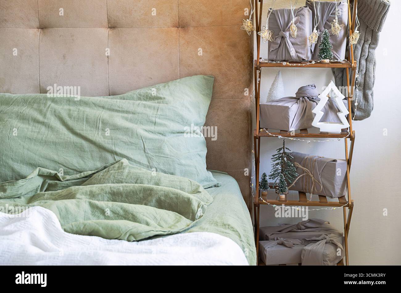 Accogliente camera da letto con decorazioni natalizie e regali ben confezionati. Interni confortevoli per le vacanze invernali. Foto Stock