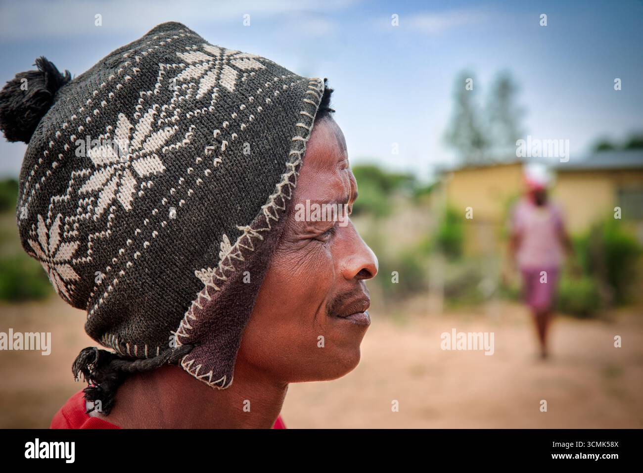 villaggio rurale, ritratto dell'uomo africano vista profilo, di fronte ad una casa, in campagna, indossa un berretto con motivi Foto Stock