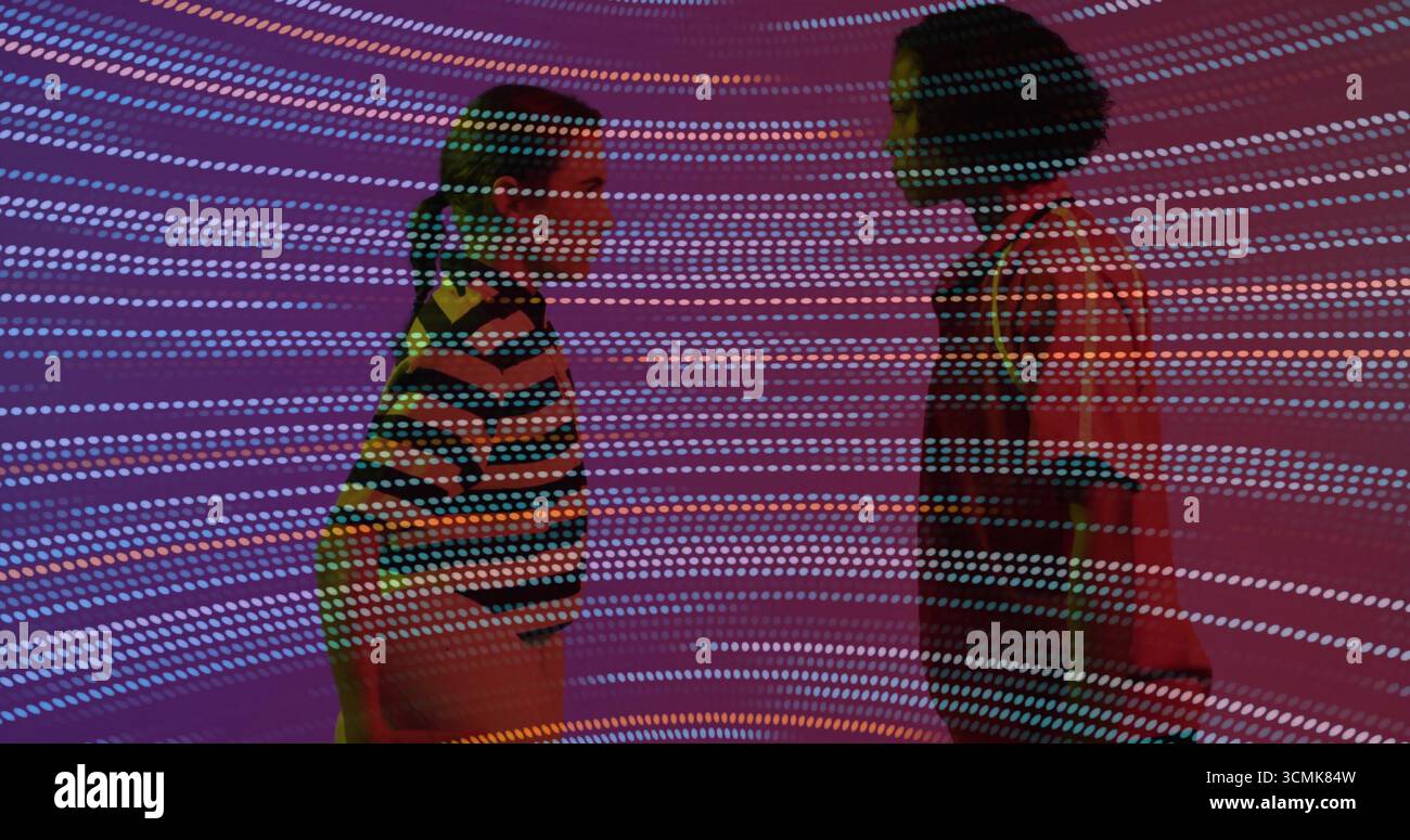 Due donne in piedi faccia a faccia nello spazio della galleria d'arte, con proiezioni di luce circolare colorata Foto Stock