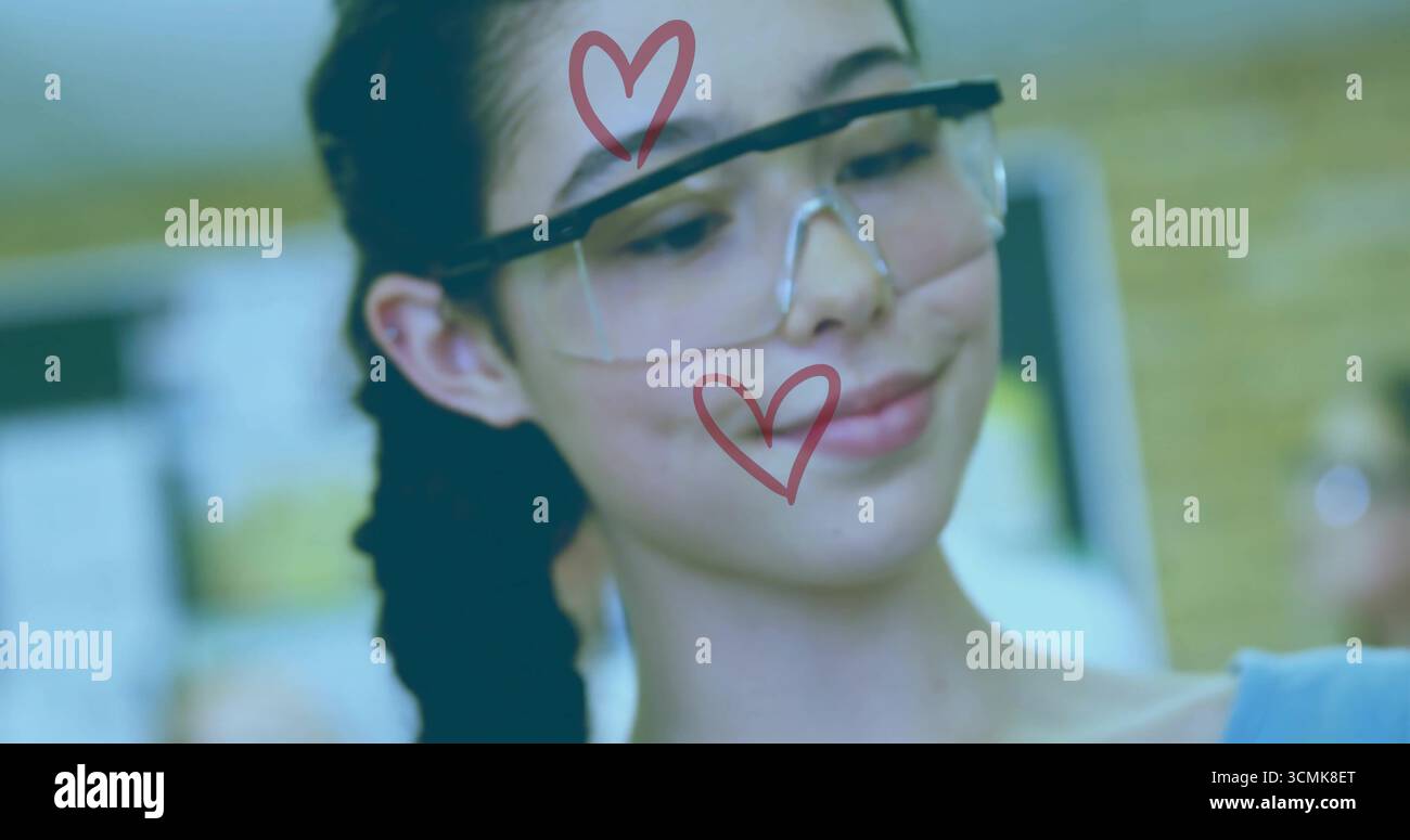 Gli studenti adolescenti testano il circuito nel laboratorio scolastico, indossando occhiali di sicurezza trasparenti con simboli rossi a forma di cuore Foto Stock