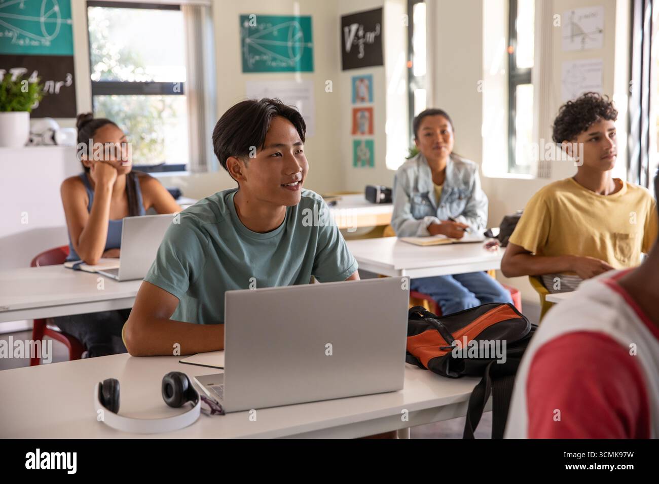 Adolescente asiatica studentessa che studia con il laptop alla scrivania della scuola con le cuffie Foto Stock