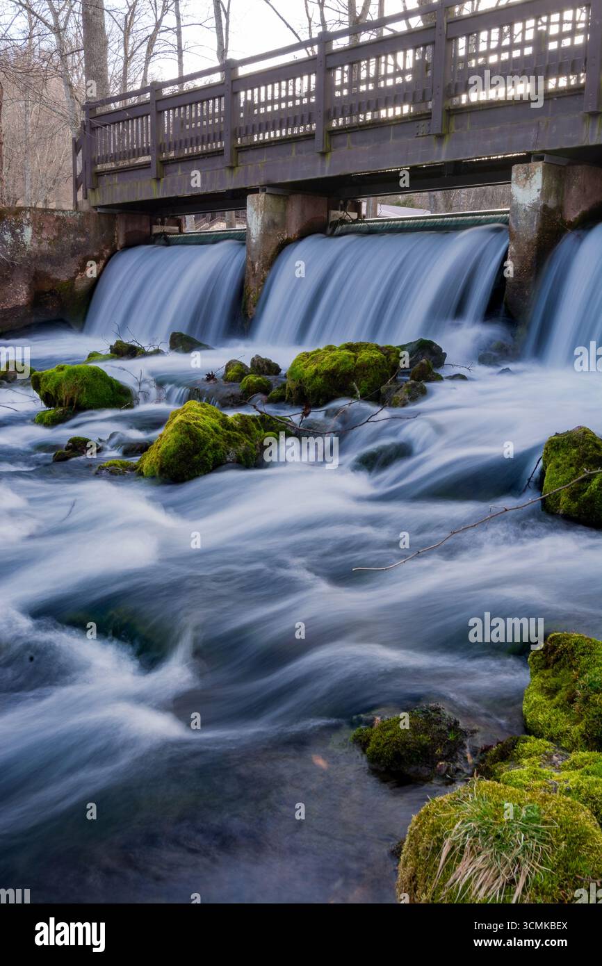 Una passerella che attraversa una piccola cascata in un parco di trote del Missouri. Foto Stock