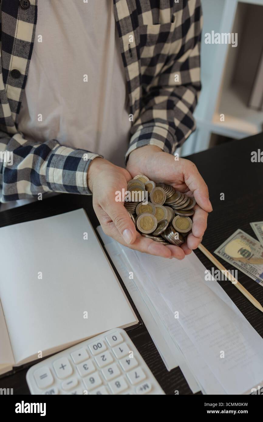 ha un sacco di monete, risparmia per la pensione, mette le monete in un salvadanaio, le pile di monete, pianifica il suo reddito e ne mette da parte alcune per il sav Foto Stock