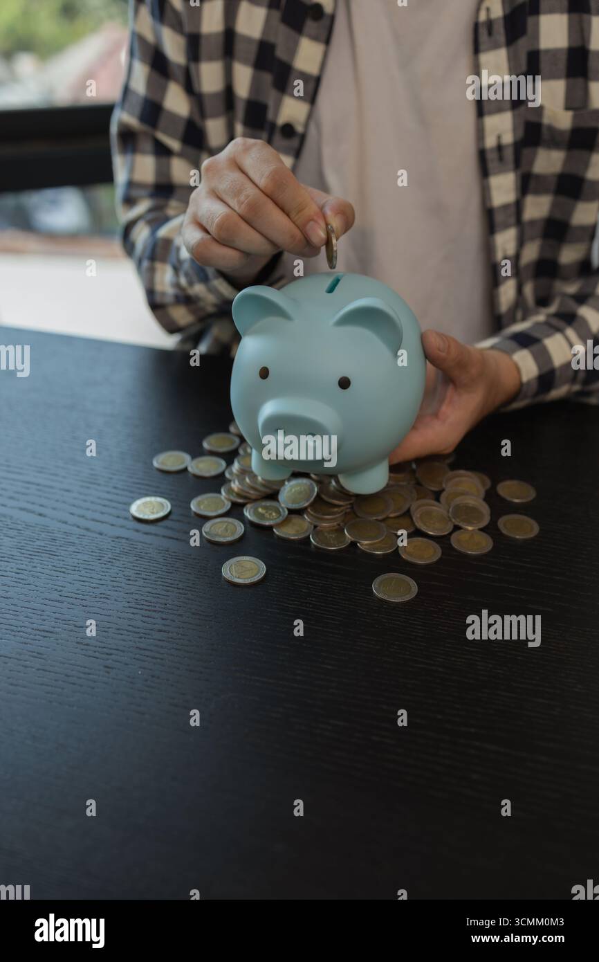 ha un sacco di monete, risparmia per la pensione, mette le monete in un salvadanaio, le pile di monete, pianifica il suo reddito e ne mette da parte alcune per il sav Foto Stock