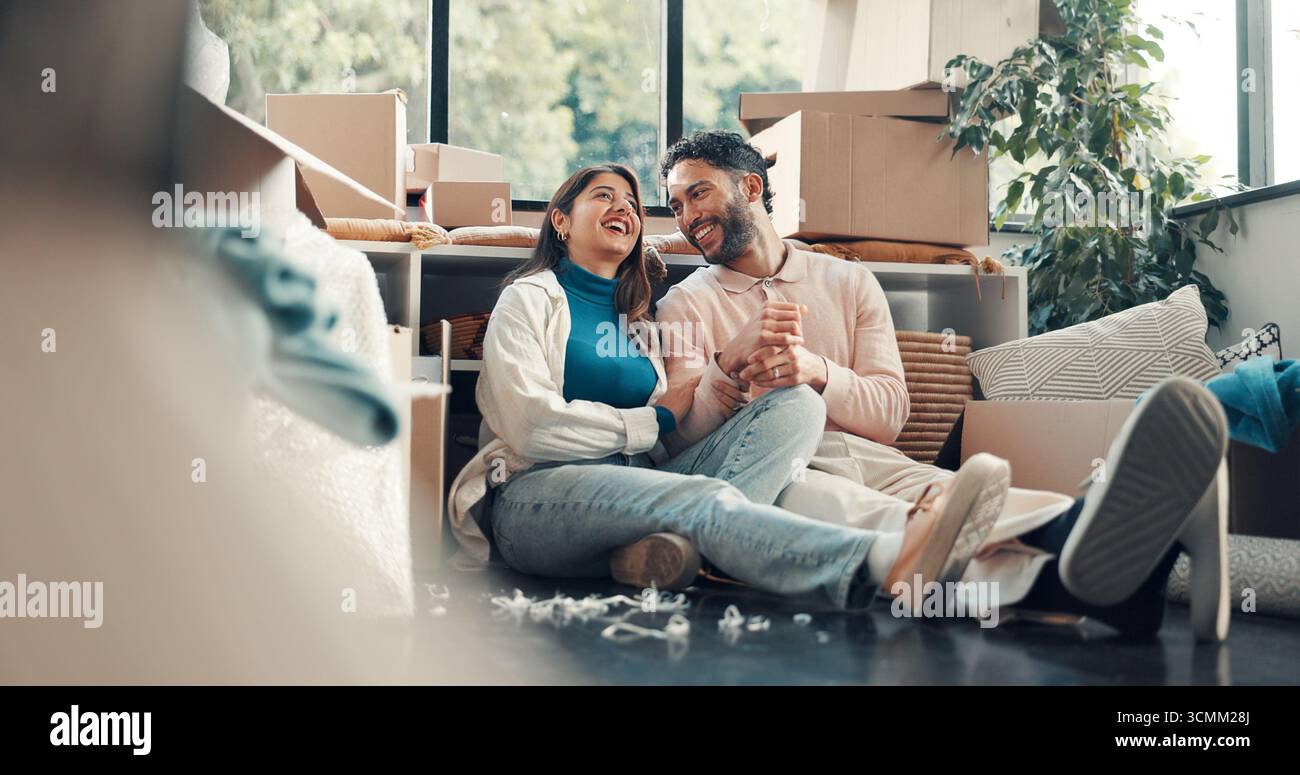 Conversazione, ridere e pianificare con la coppia in una nuova casa per investimenti immobiliari o immobiliari. Casa divertente, traslocante e visione con persone felici Foto Stock