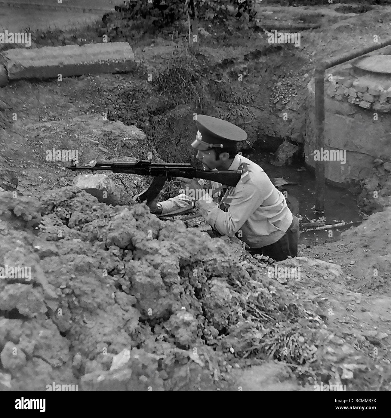 Questa fotografia d'archivio degli anni '1970-'1980 cattura un momento di un allenamento tattico per la Militsiya sovietica (polizia) a Sloviansk. Un ufficiale in uniforme prende una posizione difensiva in una trincea e mira un fucile d'assalto Kalashnikov (AK). L'immagine è un raro documentario sull'addestramento al combattimento e alle armi da fuoco per gli ufficiali delle forze dell'ordine in URSS, che riflette le realtà dell'era della Guerra fredda e i doveri della difesa civile Foto Stock