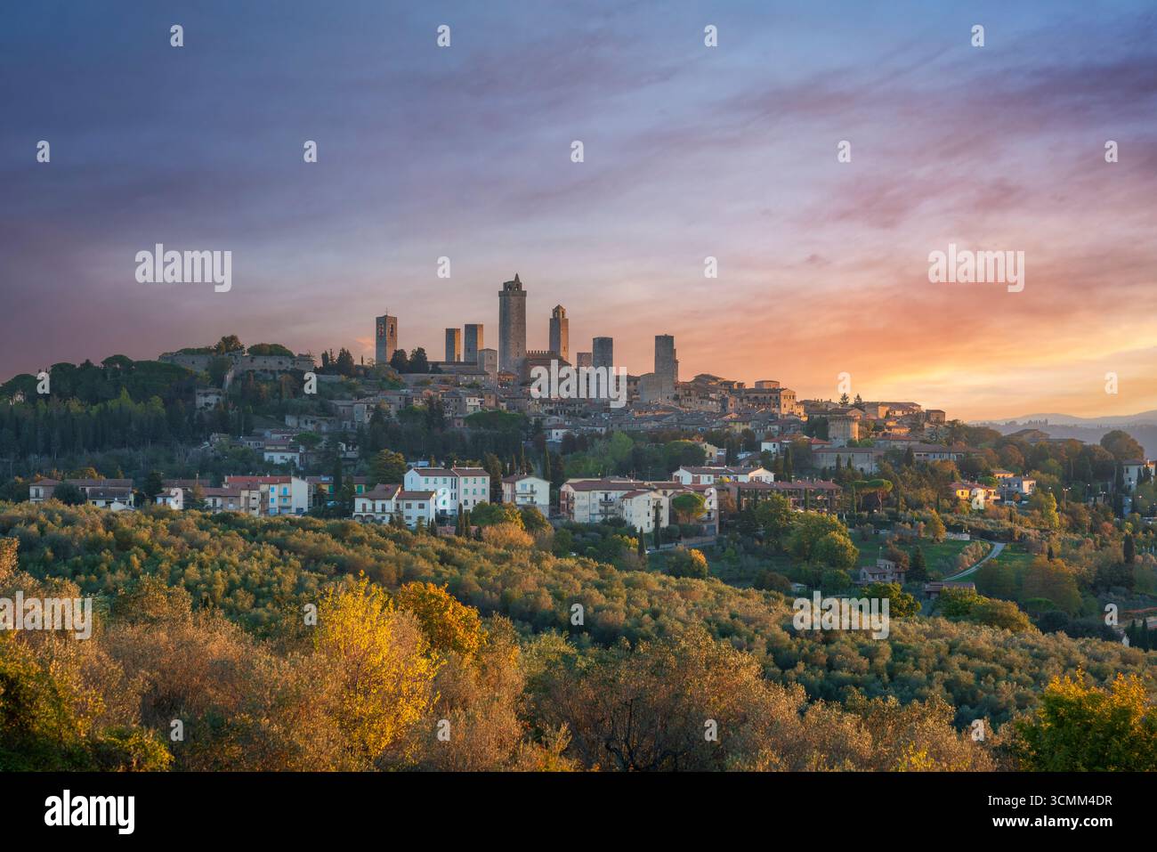 Storico skyline di San Gimignano con famose torri medievali all'alba. La luce dorata dell'alba illumina il villaggio nella campagna toscana. Provincia di si Foto Stock