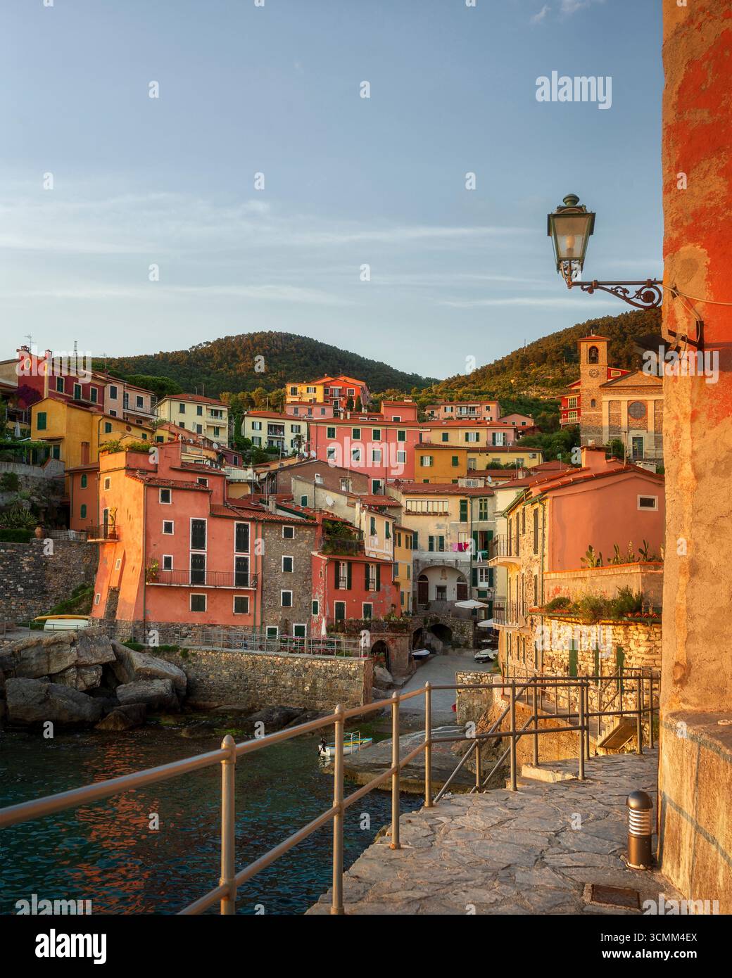 Vista panoramica del colorato villaggio di pescatori di Tellaro al tramonto dell'ora d'oro nel Golfo dei Poeti, la Spezia, Liguria, Italia. Case tradizionali e chiesa di th Foto Stock