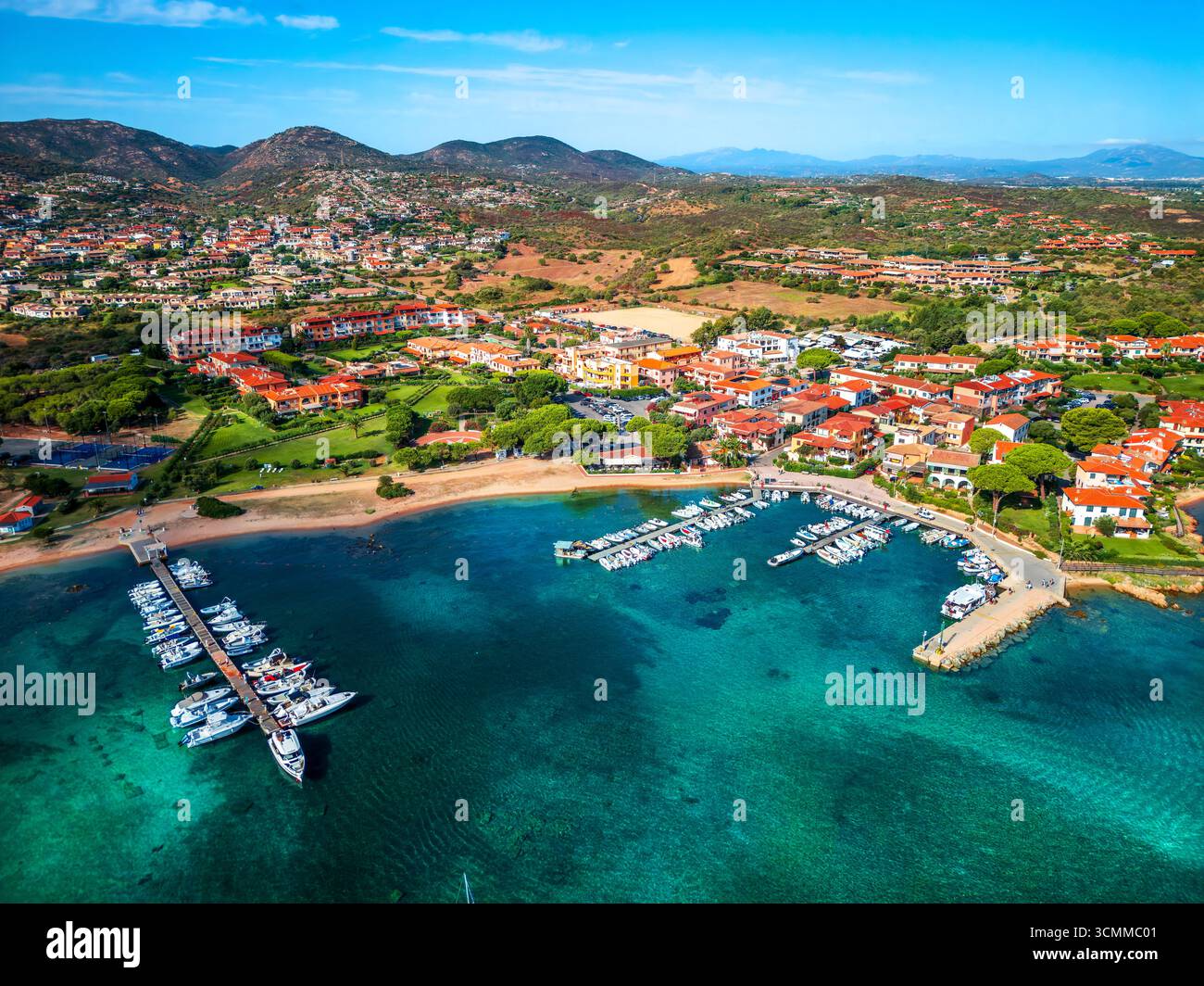 Vista aerea di un affascinante villaggio costiero mediterraneo Porto San Paolo in Sardegna, caratterizzato da acque turchesi, un porticciolo con barche e dintorni Foto Stock