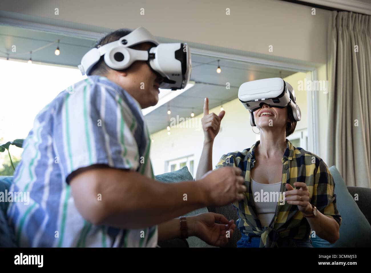 Coppia senior che sperimenta la realtà virtuale su un divano a due posti nel soggiorno con visore vr Foto Stock