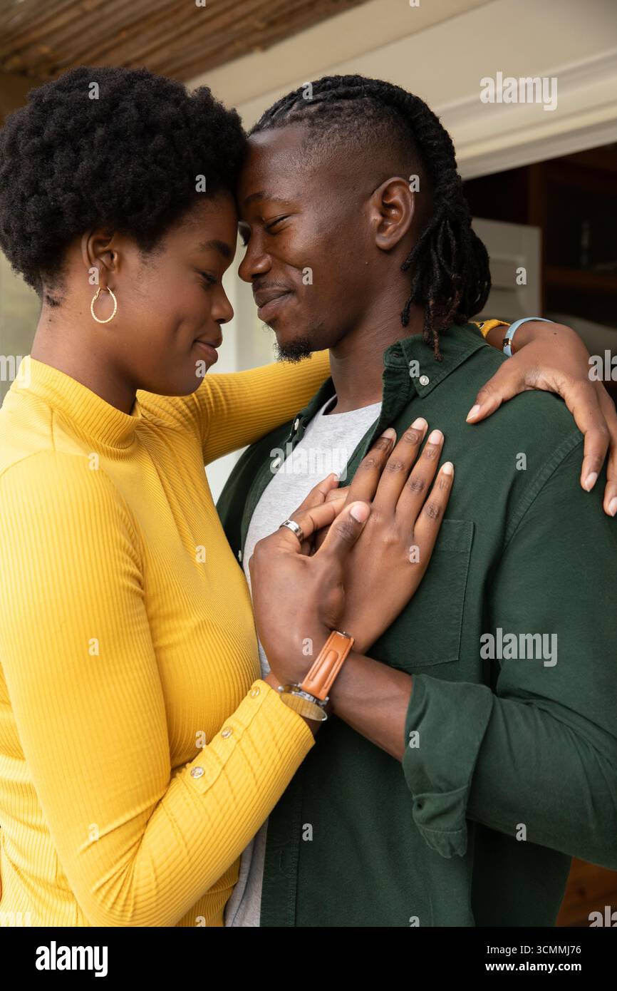 Coppia afroamericana che abbraccia la porta del portico sotto il soffitto di bambù con dolcevita Foto Stock