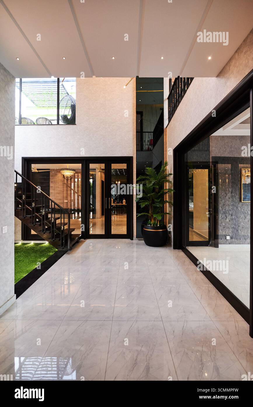 Interni moderni, spaziosi e luminosi, con grandi porte in vetro, linee pulite e un'estetica minimalista con vegetazione interna e interni di lusso Foto Stock