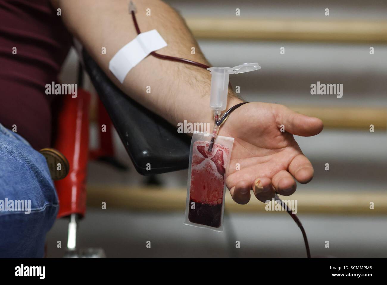 Profondità di campo poco profonda (fuoco selettivo) con la mano di un uomo che dona sangue. Foto Stock