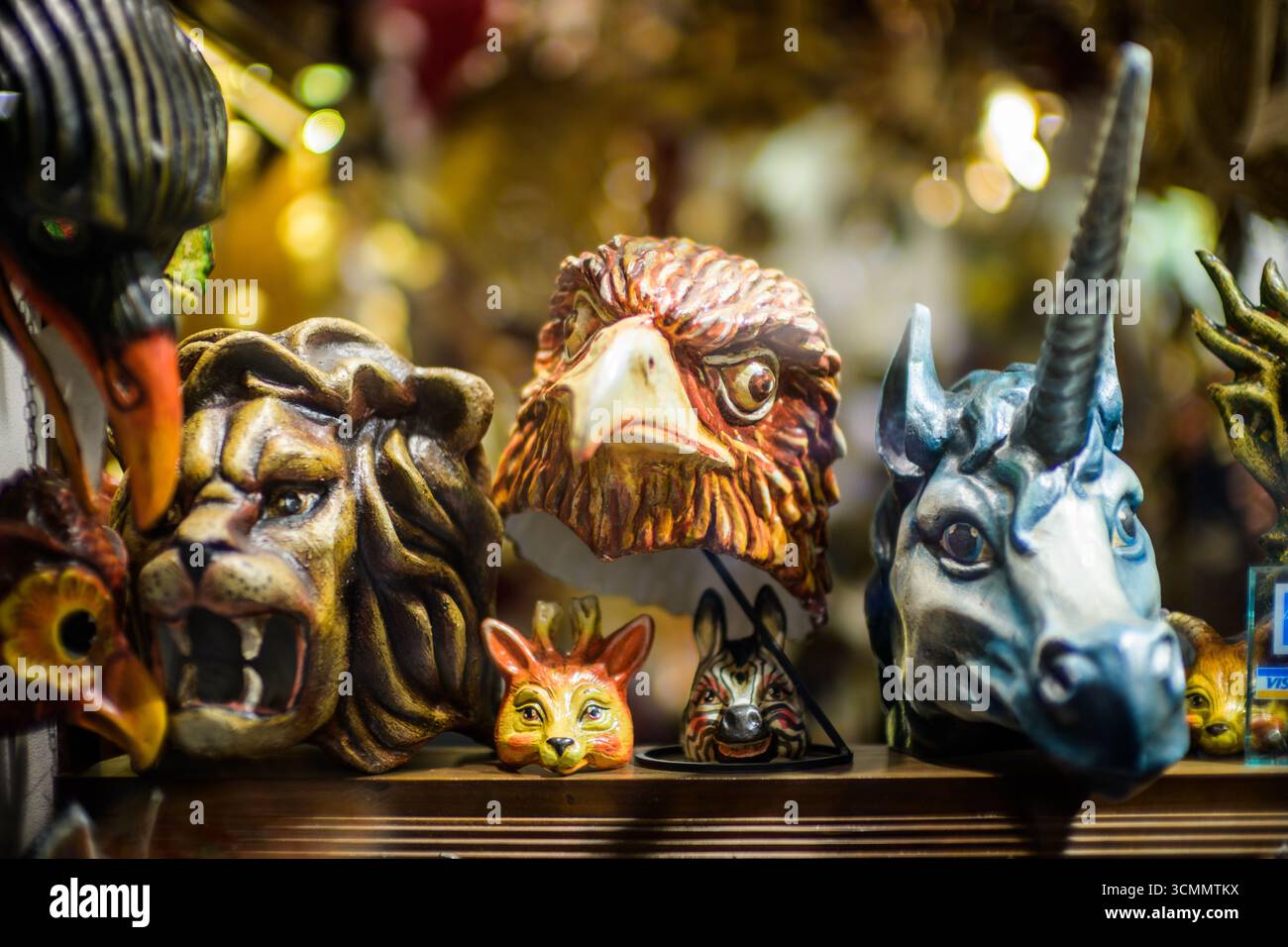 Le colorate maschere veneziane a tema animale includono un leone, un'aquila e un unicorno, che mostrano la vibrante maestria artigianale di Venezia durante l'affollato mare del carnevale Foto Stock
