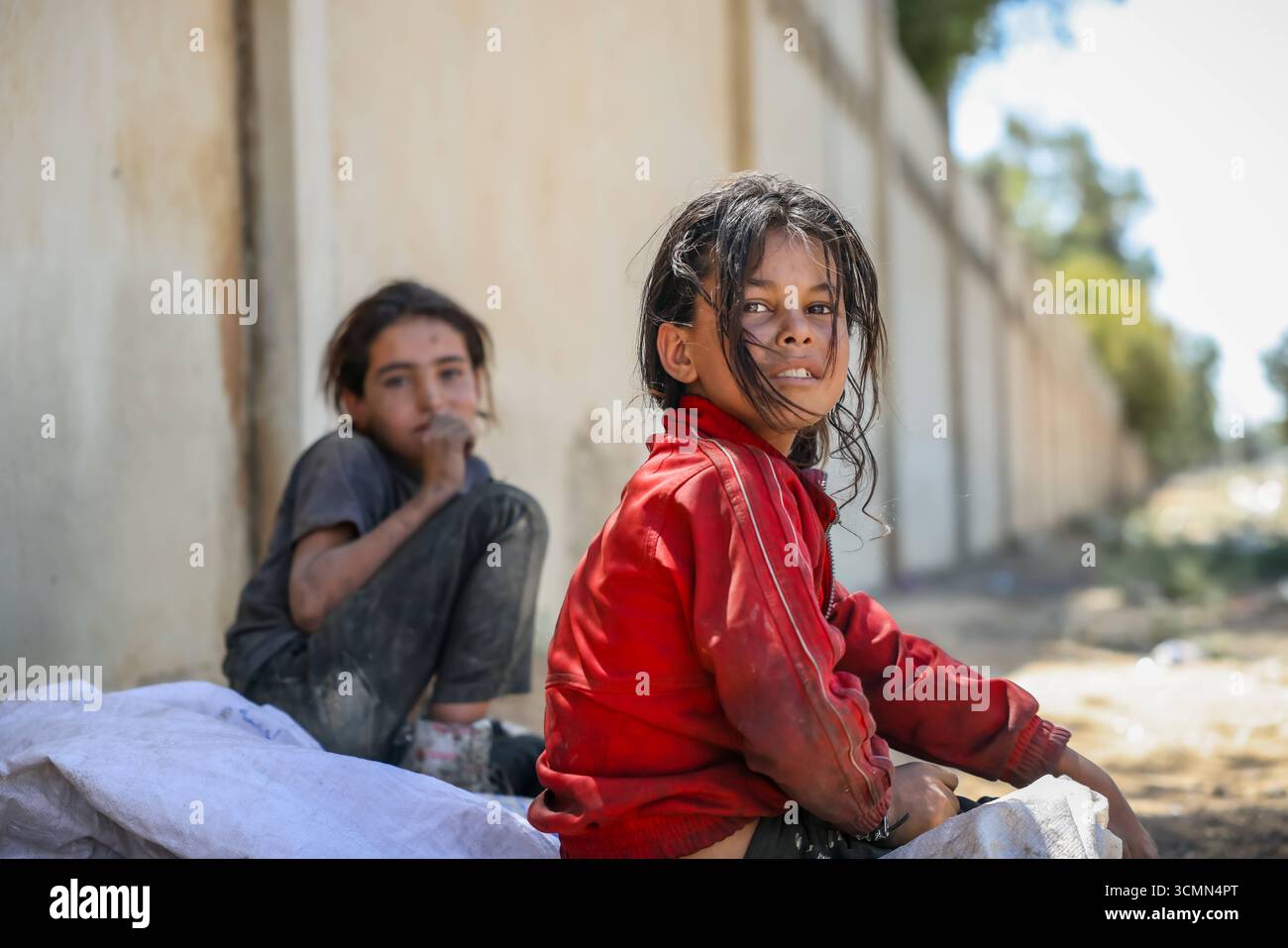Due ragazze siriane a Damasco in mezzo alle guerre successive due ragazze siriane in abiti stracciati si siedono accanto alla strada dopo aver cercato nella spazzatura di scarti di plastica da vendere per sostenere la loro famiglia a Damasco. Centinaia di migliaia di bambini nel paese continuano ad affrontare condizioni di vita difficili a causa delle conseguenze della guerra. Damasco Siria Copyright: XMohammadxBashirxAldaherx Foto Stock