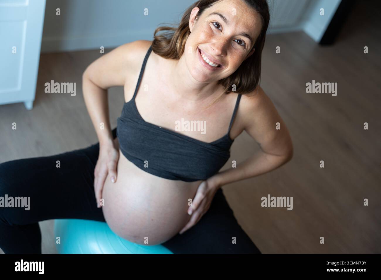 Ritratto di una donna incinta che fa l'allenamento con palla pilates a casa per una gravidanza sana Foto Stock