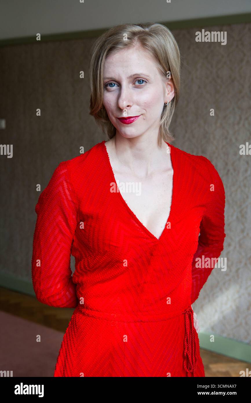 Giovane donna caucasica adulta che indossa un abito rosso in piedi in una stanza vintage. Tilburg, Paesi Bassi. MR=SÌ Foto Stock