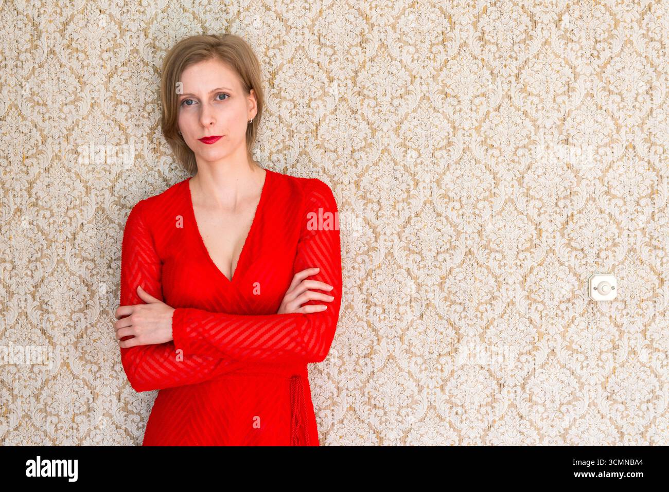 Insegnante di musica classica che indossa un abito rosso appoggiato alla parete della sala lettura. Tilburg, Nethetlands. MR=SÌ Foto Stock