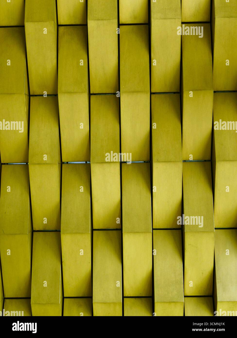 Una vista ravvicinata di una parete geometrica gialla con un pattern 3D ripetuto. Foto Stock