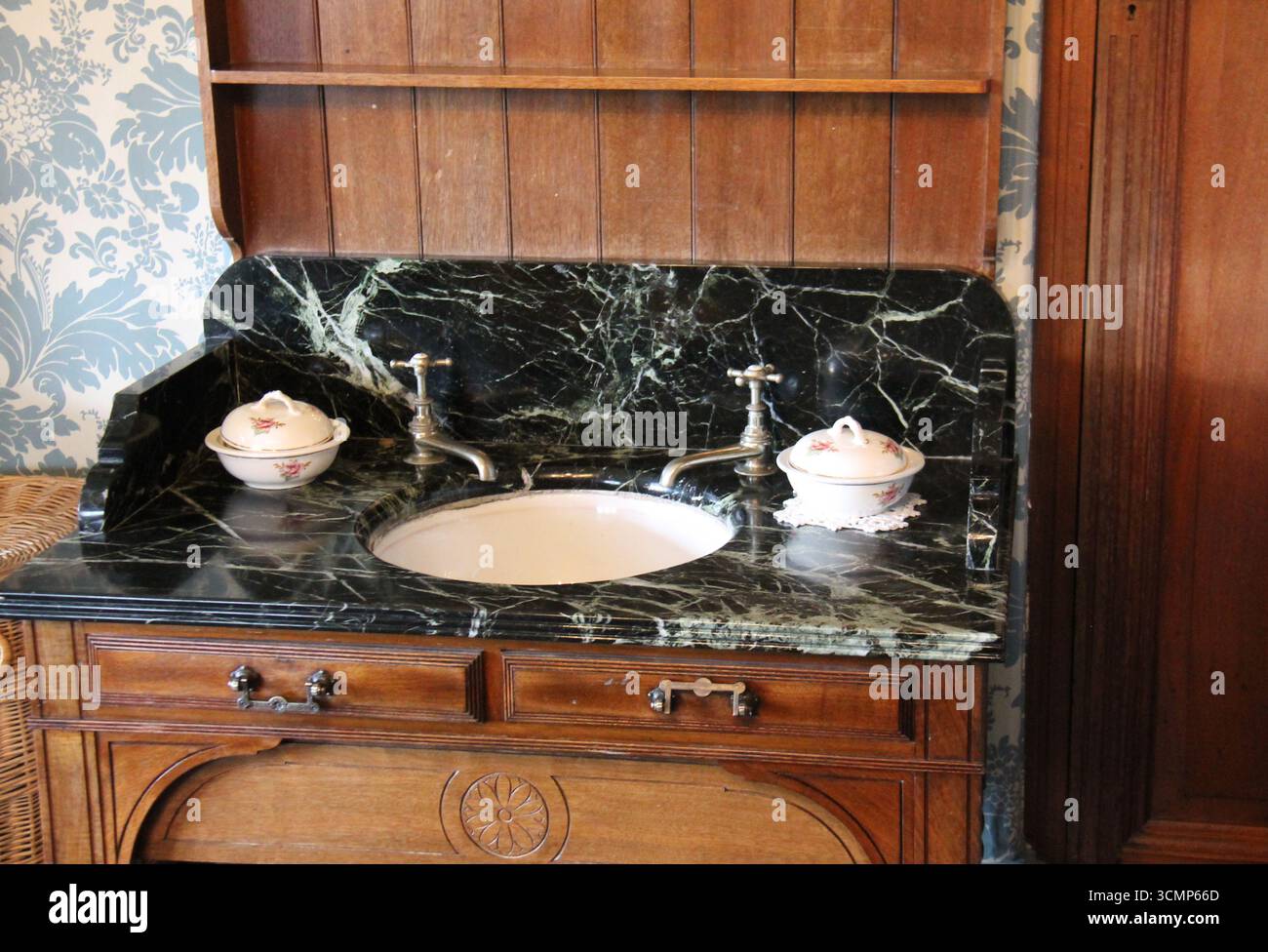 Un supporto per lavaggio con parte superiore in marmo nero con lavabo e rubinetti. Foto Stock