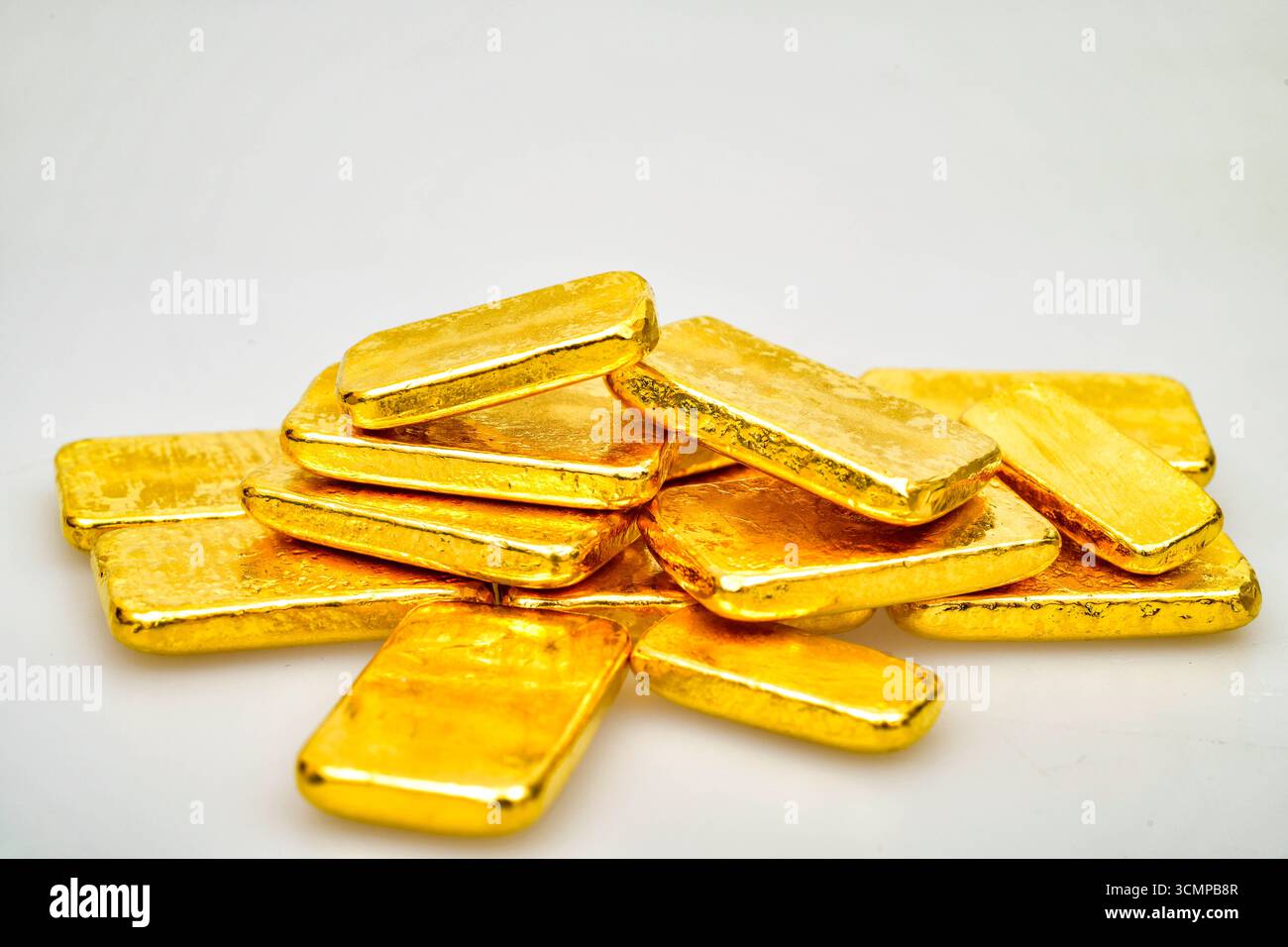 Molte barre dorate lucide su sfondo bianco Foto Stock