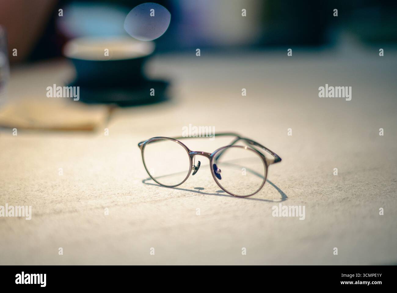 Occhiali rotondi appoggiati sul tavolo con sfondo sfocato, concetto di stile di vita minimale che simboleggia la visione, la chiarezza, la concentrazione, la lettura e l'istruzione. Foto Stock