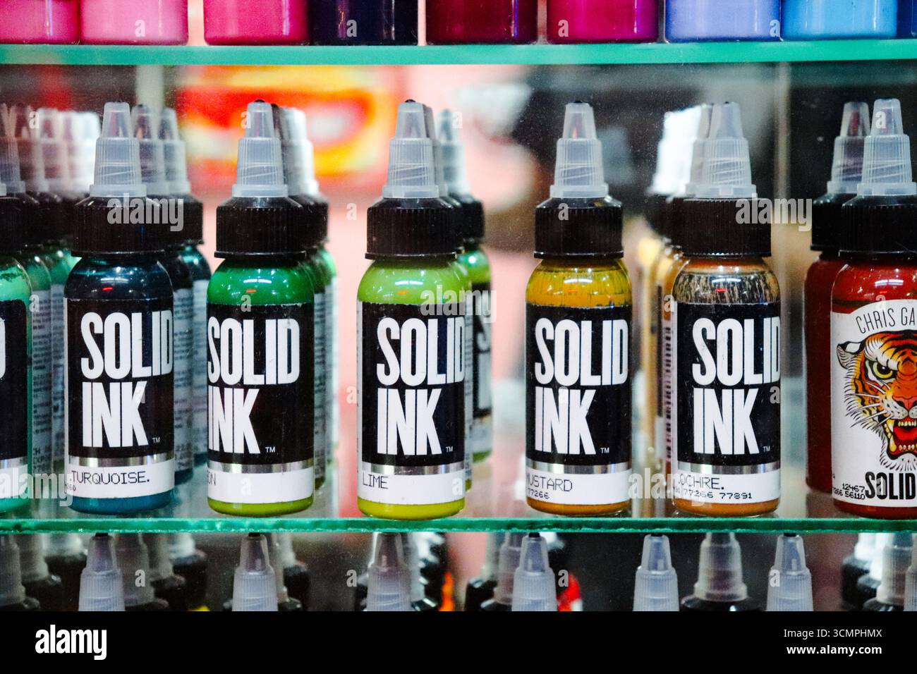 Primo piano di vari vasi di inchiostro per tatuaggi dai colori vivaci, esposti su scaffali di vetro in una finestra all'interno di Galeria Bond Street. Buenos Aires, Argentina. Foto Stock
