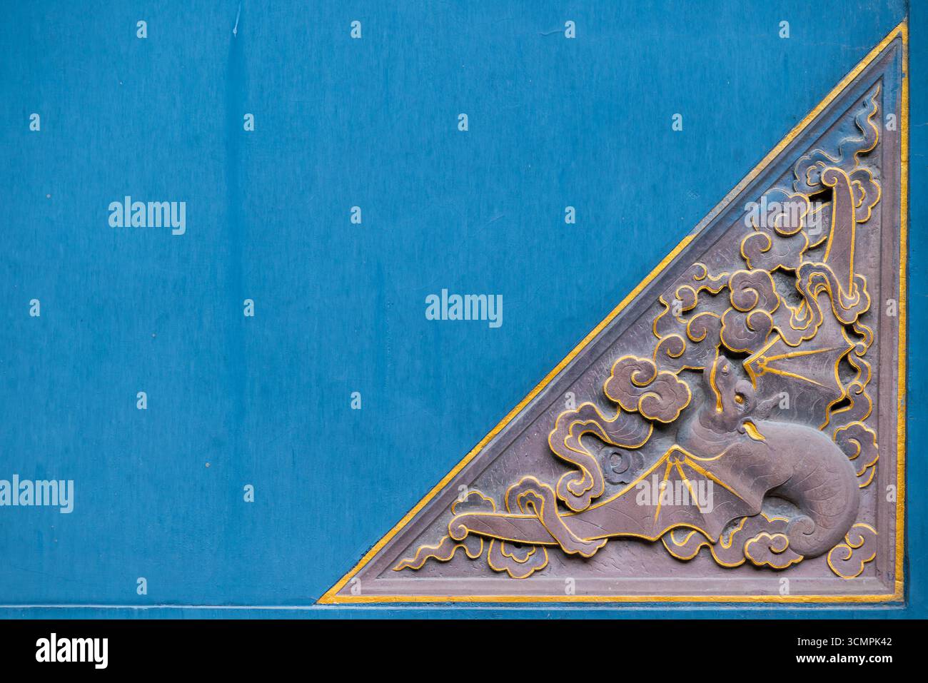 Rilievo decorativo a drago sulla parete blu che mostra arte tradizionale Foto Stock