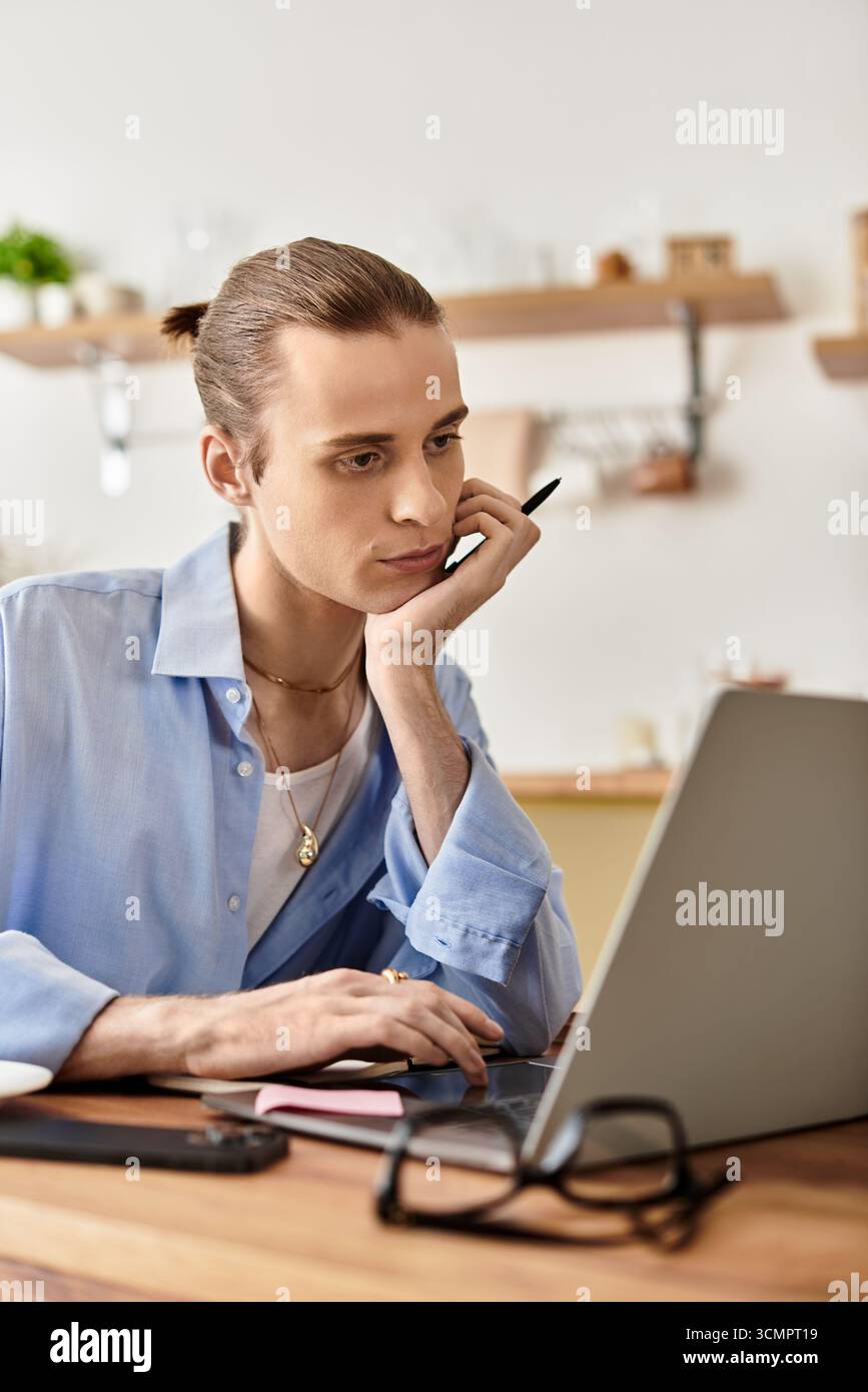 Il giovane e affascinante uomo si impegna a lavorare con cura su un notebook, circondato da un'atmosfera calda. Foto Stock
