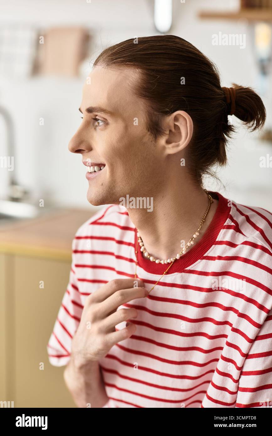 Un giovane allegro dallo stile femminile gode di un momento di luce in una cucina accogliente. Foto Stock
